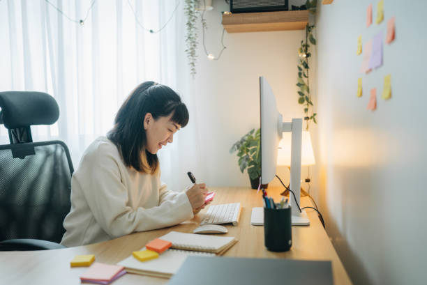 istock Asian businesswoman writing notes in her notebook behind her office desk 1567671171