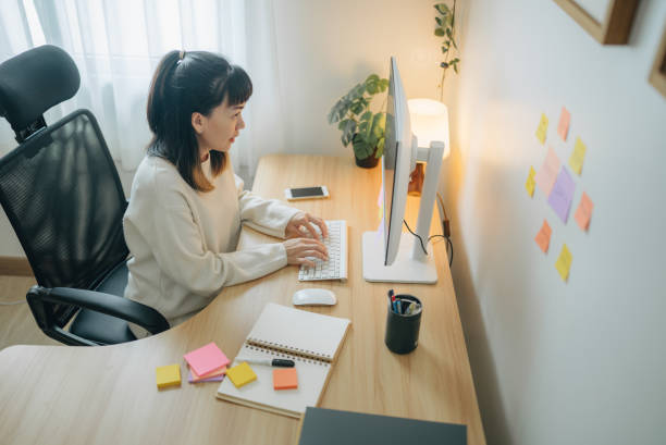 istock Asian businesswoman writing notes in her notebook behind her office desk 1567672740