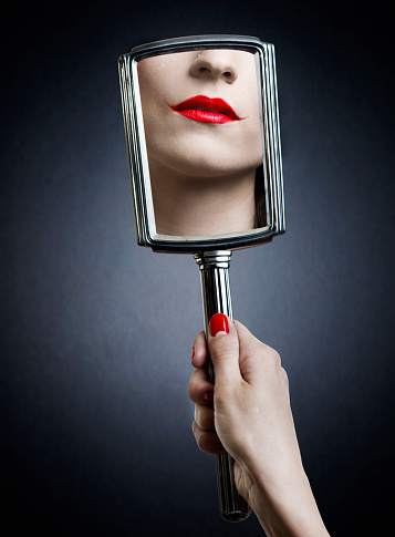 Joker make-up in reflection of hand mirror