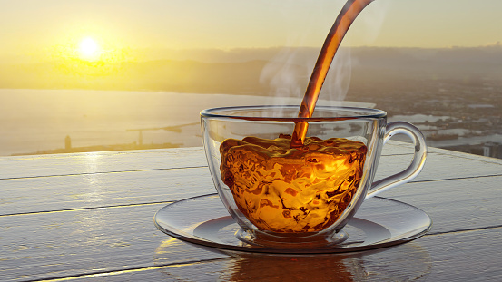 Poring tea to a glass cup on a wooden table with sunset sky in background (3D Rendering)