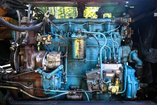 Diesel engine of an old tractor. Lots of metal tubes. Painted in blue. Close-up. Selective focus.