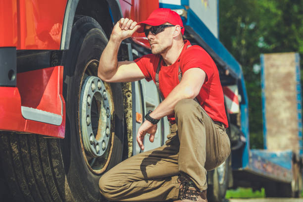 Truck Driver on Scheduled Rest Stop Professional Trucker Resting Next to His Red Semi Truck During Scheduled Driving Rest Stop. Trucking and Transportation Industry Theme. stopover stock pictures, royalty-free photos & images
