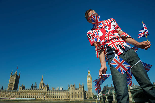 Man wrapped in Union Jack British flags bunting stands tangled at the London skyline in front of Westminster Palace and Big Ben
