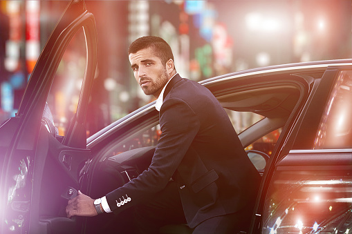 Portrait of an elegant man driving a car, luxury nightlife,.man in a car at night.