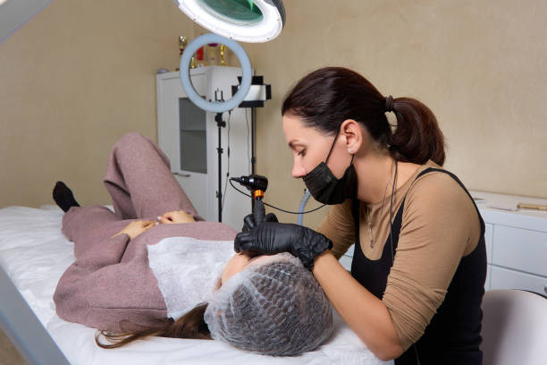 Female doctor uses professional tattoo machine for permanent makeup