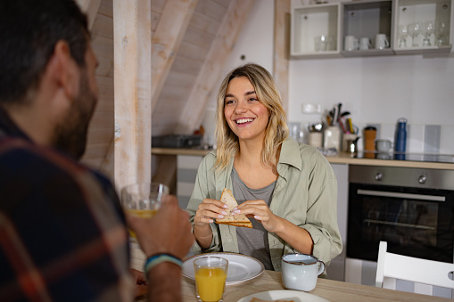 Young happy woman communicating with her boyfriend during a meal at dining table.
