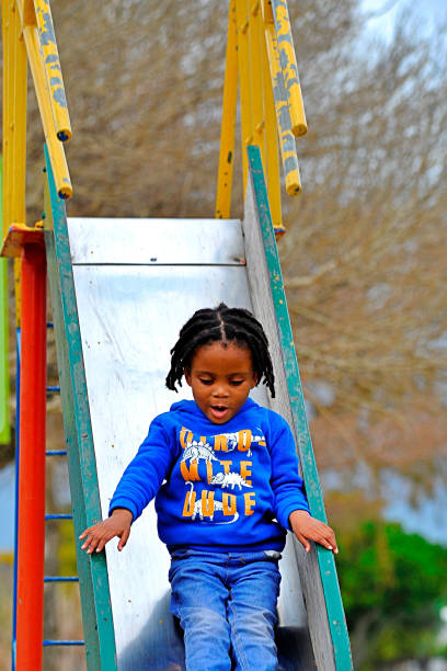 beautiful young black African boy with dreadlocks playing in a park .