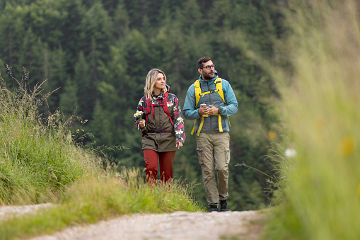 Young couple of hikers walking through wilderness. Copy space.