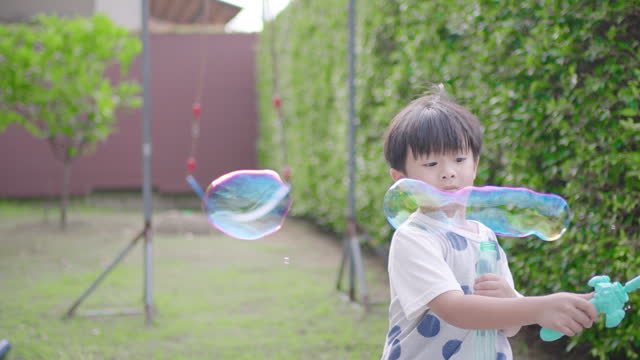 Little boy playing soap bubbles in the front yard.