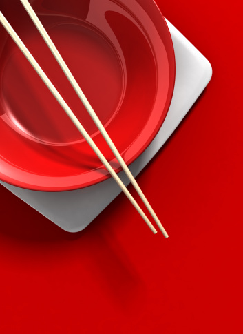 A red asian place setting with cop sticks on a red table. Very high resolution 3D render.