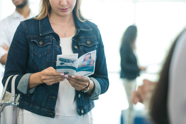 une femme méconnaissable lisant une brochure bancaire fait la queue - decisions women thinking latin american and hispanic ethnicity photos et images de collection