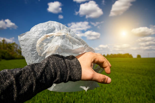 istock Plastic bag in hand on the background of a green field. Global problems with garbage. environmental pollution. 1567851937
