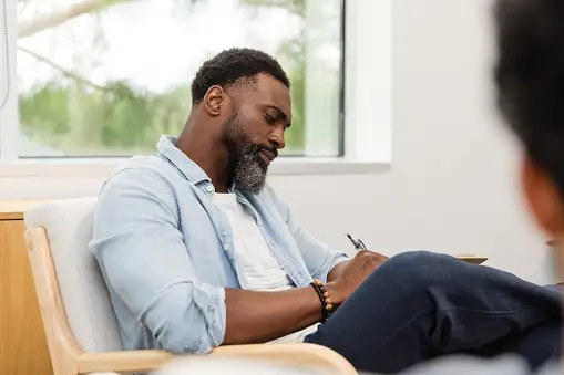 Serious, forbidding male counselor documents unrecognizable patient's story