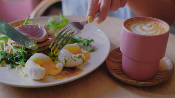 istock Female hands is cutting a poached egg. Yellow liquid slow motion. 1567883254