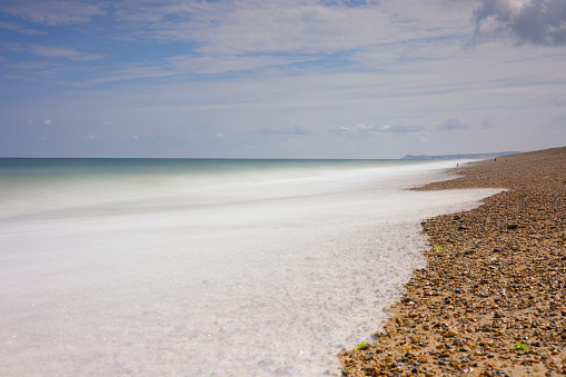 Long exposure capturing the motion of waves on the shingle beach at Cley Next The Sea, Norfolk.