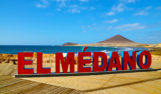 Letters with the name of El Medano next to the volcanic sand beach and the Red Mountain in the background.Tenerife,Canary Islands,Spain.Travel concept.