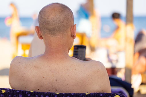 A man enjoying a serene moment on a beach chair, using his phone.