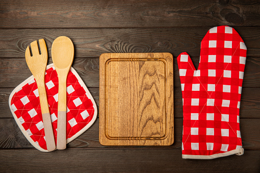 Wooden kitchen utensils, cutting board, potholder and glove on the table, top view. Kitchen Mitten and protective oven mitts on the table. Kitchenware. Kitchen accessories.Close-up.top view.
