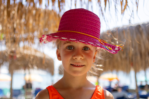 The beach becomes a playground for a cheerful girl in her bright red hat.