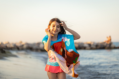 A girl captivated by the beauty of the sea, adorned in her poncho.