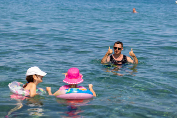 istock Dad and Little Sisters in the Water 1567919957