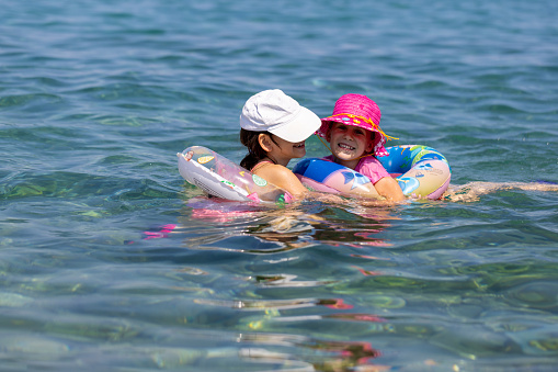 The bond between two sisters shines as they share a delightful swim in the sparkling sea.