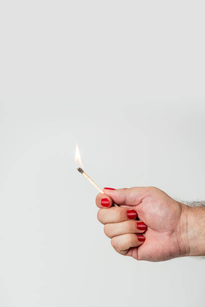 istock Male hand with red fingernails hold burning matchstick 1567925259