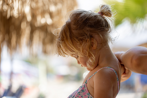 Mom prepares her excited daughter for a splashy adventure, dressing her up in a lovely swimsuit.