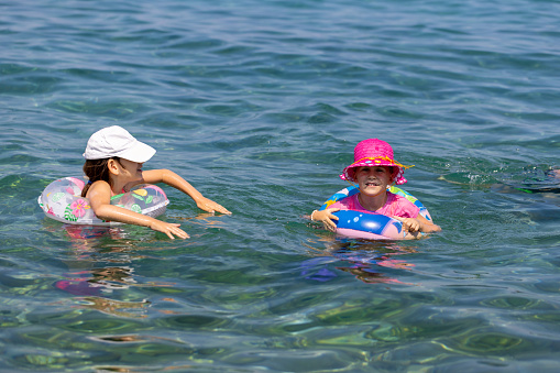 Little sisters enjoy a fun-filled day at the beach, swimming and exploring the sea.