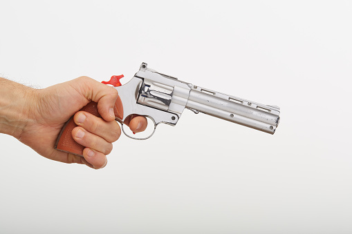 Hand holding a toy gun against a white background