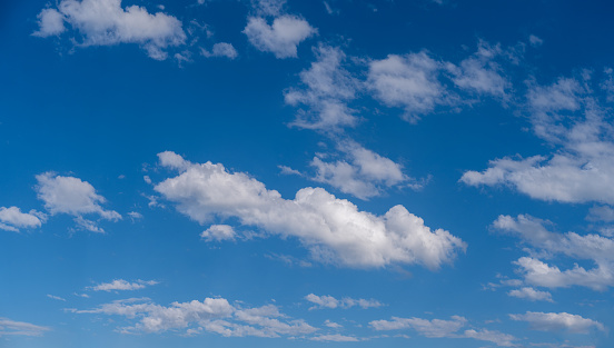 Bright, cumulus clouds in front of a clear blue sky.