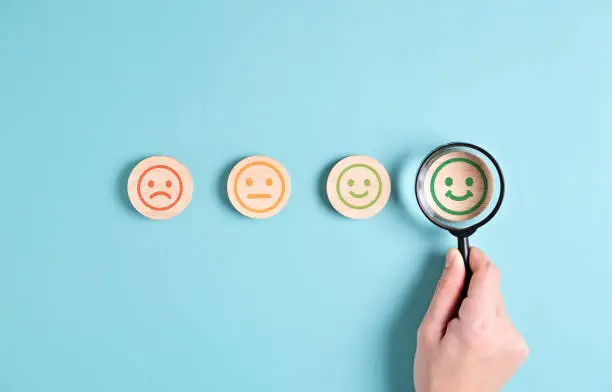 Photo of satisfaction with smiley face emoticon on wooden yellow background.