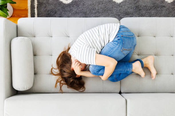 istock Frustrated woman covering face and crying, lying on sofa at home alone 1567958566