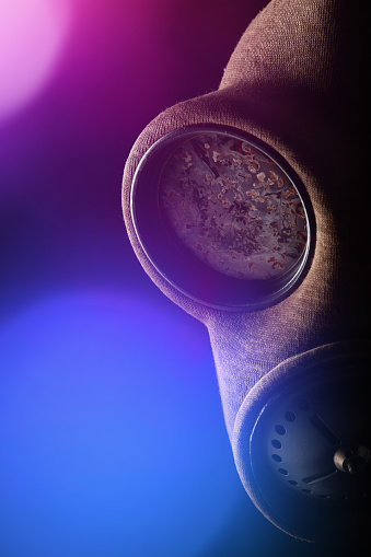 Old-fashioned military gas mask in the dark with lens flare and bokeh balls on black background