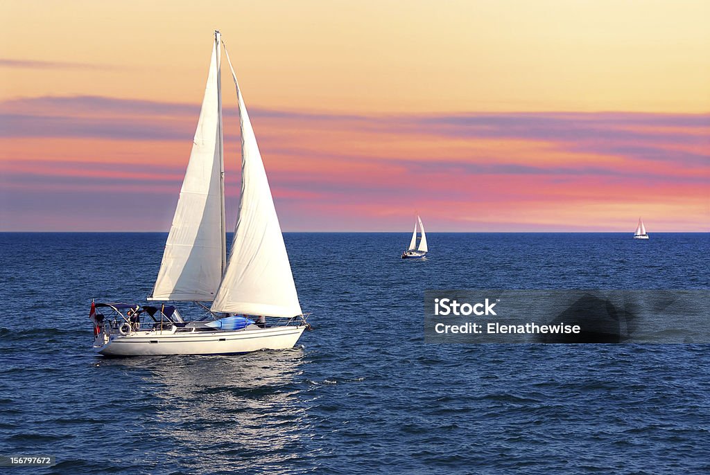 Sailboats at sunset Sailboat sailing towards sunset on a calm evening Sailboat Stock Photo