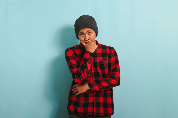 istock Thoughtful Young Asian man holds his chin, making plans, isolated on a blue background 1567994482