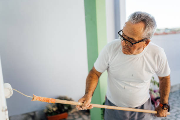Elderly man painting the wall
