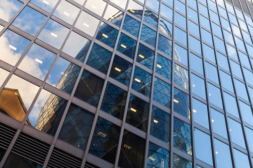 London, United Kingdom - April 25, 2019: Exterior of modern office building with reflection of the Gherkin in shiny windows. London city street view