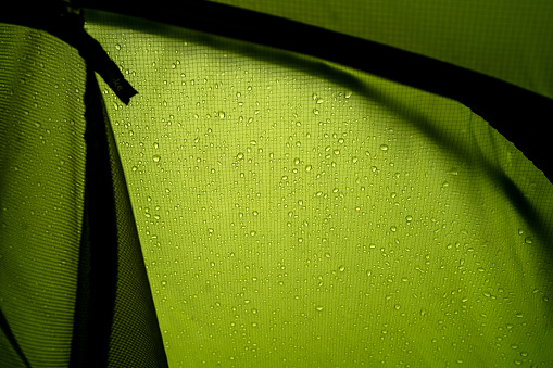Rain drops on the touristic tent, close-up shot from inside of the tent