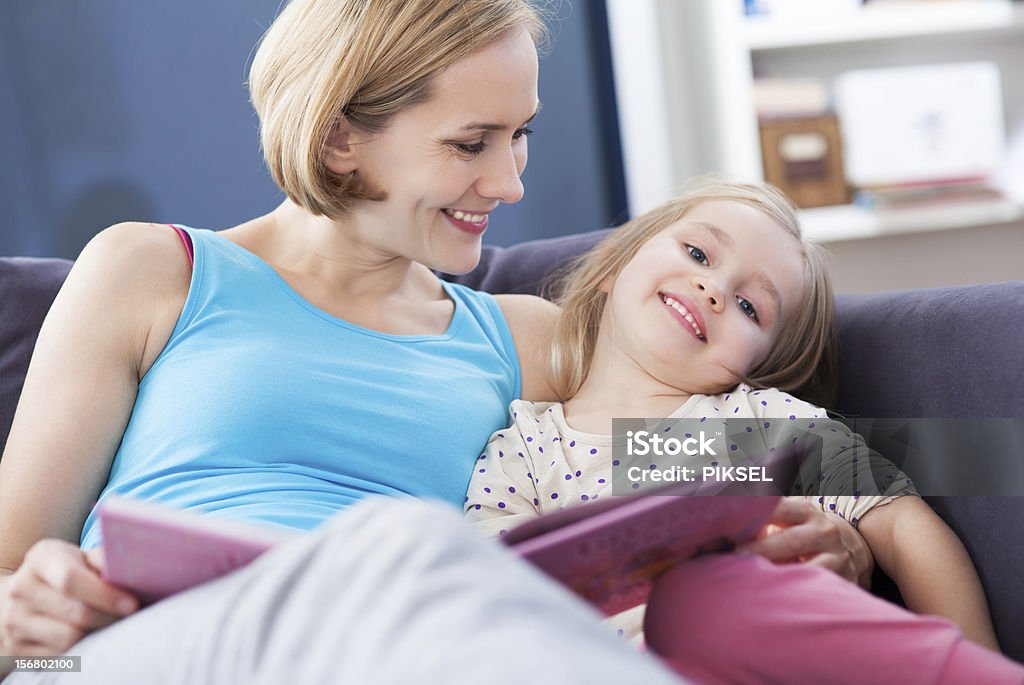 Mother and daughter reading on the couch Adult Stock Photo