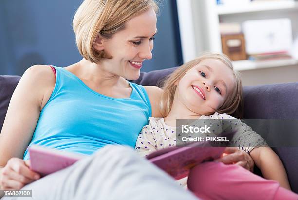 Mother And Daughter Reading On The Couch Stock Photo - Download Image Now - Adult, Book, Child