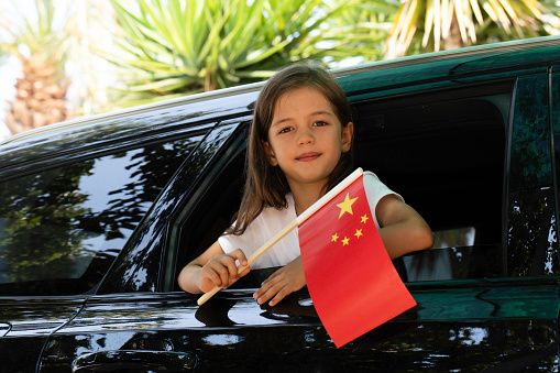 Girl holding Chinese flag in the car.