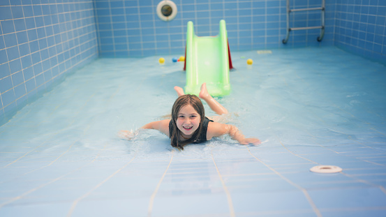A small girl is enjoying in a partially filled pool in summer.