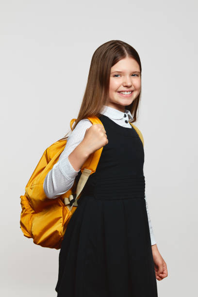 istock Excited girl with yellow backpack and arm raised smiling happily while celebrating success at school 1568080355