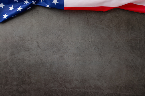 Captivating public holiday scene with this top-view image, featuring American flag on a grunge textured grey concrete background. Great for advertisements or text overlays during the festive occasion