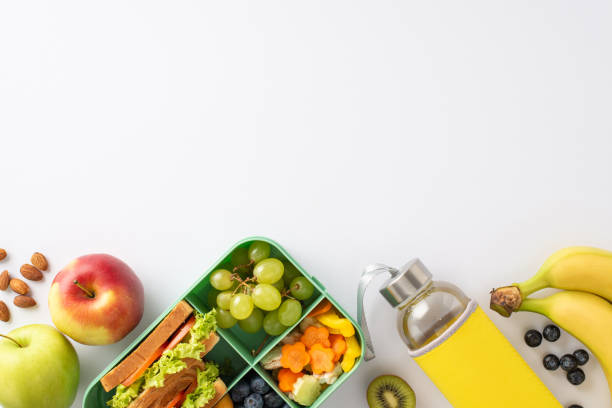 istock Capture essence of break snacks in educational process with top view photo showcasing lunch box and fruits, water bottle on white isolated backdrop, providing ample room for text or advertising. 1568181752