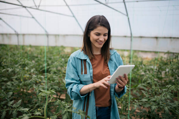 istock Smiling woman using digital tablet in greenhouse 1568181891