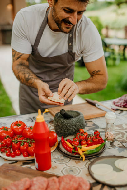 istock Handsome mid aged Man Cooking Delicious BBQ Meal in His Outdoors Summer Kitchen 1568182333