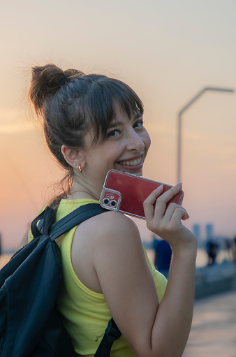 A woman in a yellow shirt dealing with her phone at sunset a young woman