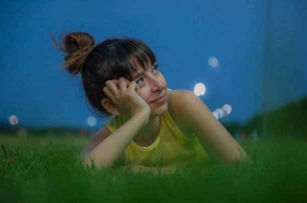 Young woman daydreaming lying on the grass in the evening